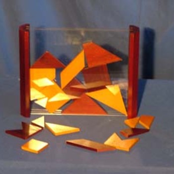 Batik - 
But : le plateau de jeu est un tableau vertical ... transparent ! 18 pièces de bois, de formes géométriques variées, vont y être insérées une à une, en laissant quelques vides... Gare à celui dont la pièce ne rentre pas complètement dans le tableau : il a perdu !