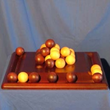 Pylos - 
But : les joueurs placent des billes sur le plateau de manière à former une pyramide. Le joueur qui place la dernière bille au sommet gagne la partie.